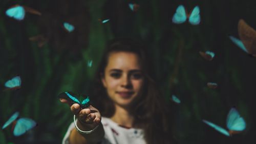 Portrait of a smiling young woman holding beautifly outdoors