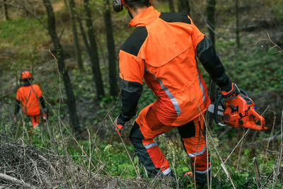 Man holding a chainsaw cut trees. lumberjack at work. gardener working outdoor in the forest. 