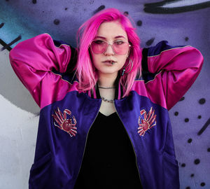 Portrait of beautiful young woman standing against wall