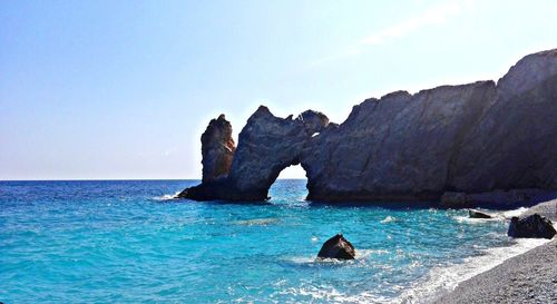 Rock formation in sea against blue sky