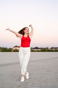 Full length portrait of woman standing against sky during sunset