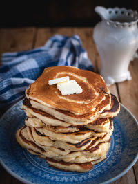 Stack of pancakes with butter on wooden background