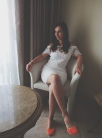 Portrait of young woman sitting on sofa at home