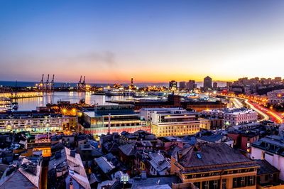 Illuminated cityscape against sky during sunset