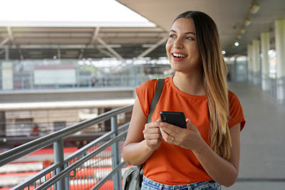 Brazilian girl walking in train station holding smartphone in sao paulo, brazil