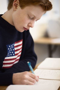 High school boy writing at desk in classroom