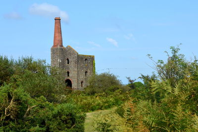 Old building by trees against sky