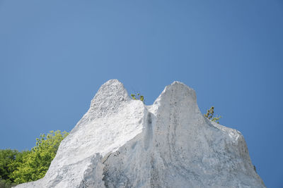 Low angle view of rocks against clear blue sky