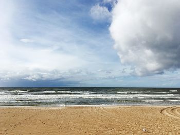 View of calm beach against cloudy sky