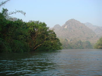 Scenic view of river by mountains against clear sky