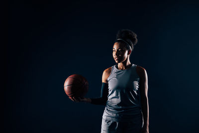 Side view of young woman standing against black background