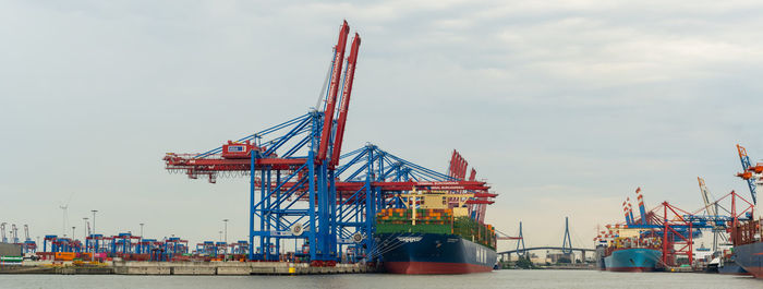 Cranes at pier against sky