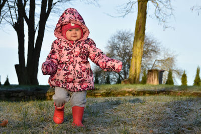 Cute girl walking on grass against trees