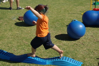 Girl playing soccer ball on grassy field