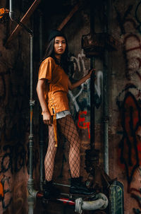 Portrait of woman standing against graffiti wall