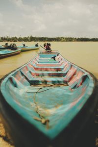 Boat moored in lake against cloudy sky