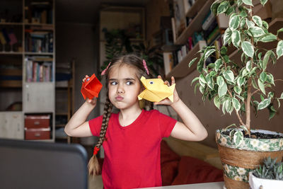 Portrait of cute girl holding camera at home