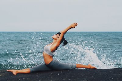 Woman practicing yoga on the beach 