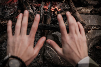 Cropped hands of man gesturing against campfire