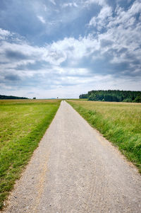 Road amidst field against sky