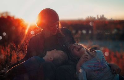 Rear view of mother and daughter against sky during sunset