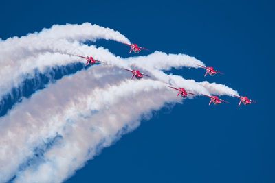 Low angle view of airplanes flying against blue sky