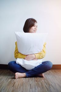 Woman sitting on floor against wall at home