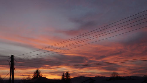 Low angle view of silhouette electricity pylon against romantic sky