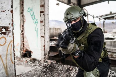 Portrait of army soldier aiming rifle while in building