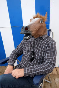 Man in horse mask sitting on chair