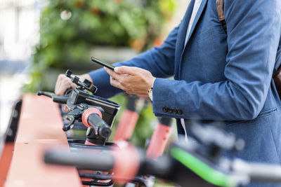 Young businessman unlocking electric push scooter through smart phone