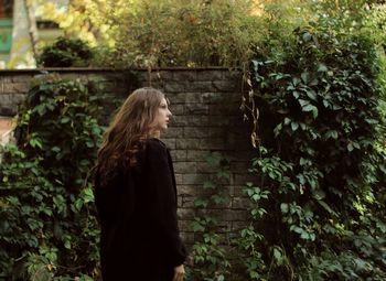 Rear view of woman standing against plants