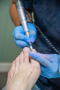 A master in a beauty salon makes a hardware pedicure to a client, soft focus