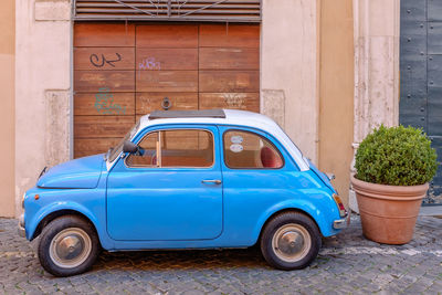 Vintage car parked against blue wall