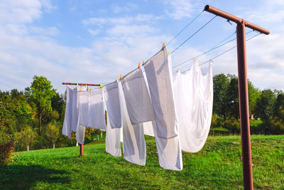 Clothes drying on clothesline on field against sky