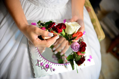 Midsection of bride holding flowers