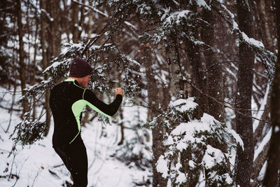 Man exercising by tree on field during winter