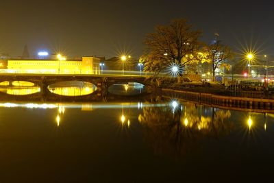 Illuminated bridge over river in city at night