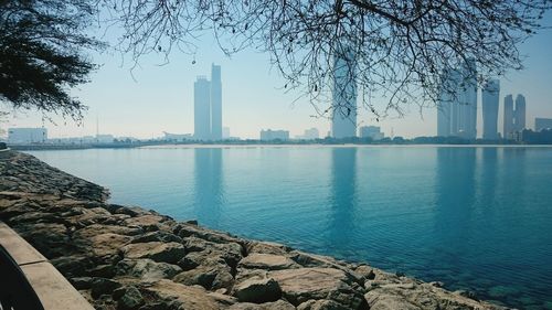 Scenic view of river by buildings against sky