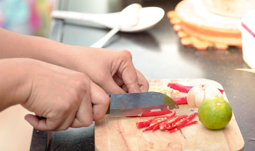 Cropped hands of woman cutting garlic in kitchen