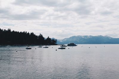 Boats in lake tahoe by against cloudy sky