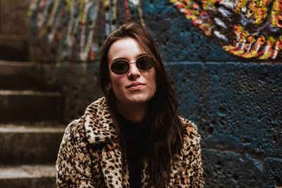 Portrait of young woman sitting on staircase by wall