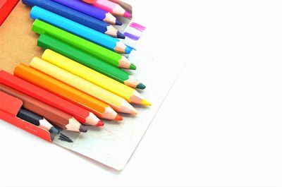 High angle view of multi colored pencils on white background