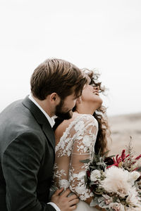 Couple kissing on white flower against clear sky