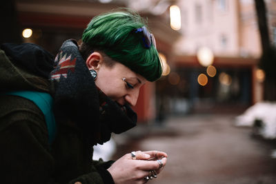 Portrait of happy non-binary hipster woman using smart phone in city