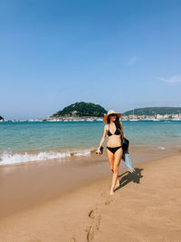Full length of woman standing at beach against clear sky