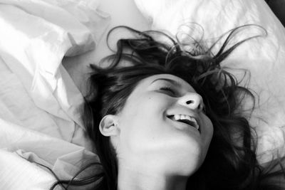 High angle view of happy young woman lying on bed