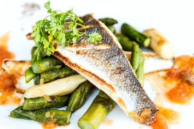 Close-up of fish with asparagus served on table