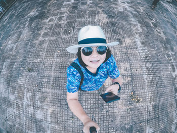 High angle portrait of mid adult woman using mobile phone while standing on footpath