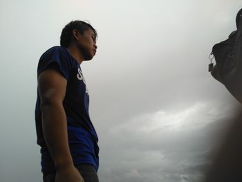 Side view of man standing against sky